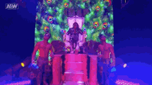 a woman is sitting on a throne with peacock feathers in the background while two men stand behind her .