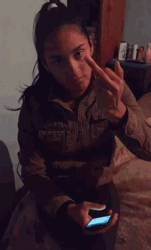 a woman giving the middle finger is holding a cell phone