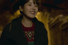 a woman wearing a black jacket and a red shirt with the word max on it smiles