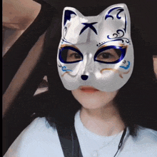 a woman wearing a white cat mask with a blue eye