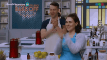 a man and a woman are clapping in a kitchen with the words bake off argentina on the wall behind them