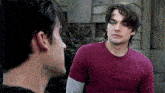 a man in a red shirt is looking at another man