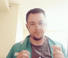 a man wearing headphones and a green jacket looks at the camera .