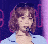 a woman wearing sunglasses and a microphone has a tattoo of cherries on her face