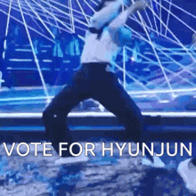 a person is dancing on a stage with the words `` vote for hyunjun '' written on the bottom .