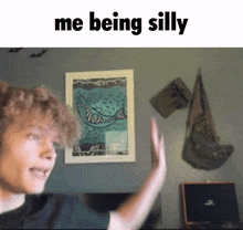 a man with curly hair is giving a high five in front of a painting that says me being silly