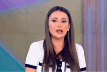 a woman with long hair is standing in front of a television screen and making a funny face .