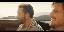 two men are sitting in the back seat of a car smiling .