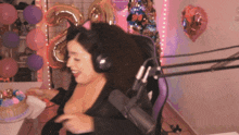 a woman wearing headphones and a cat ear headband holds a cake