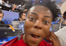 a man in a red shirt is making a surprised face in front of a screen that says 1-0