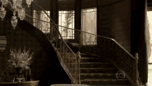 a black and white photo of a staircase with a chandelier in the background