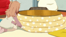 a girl sitting on the floor looking at a round table with white polka dots