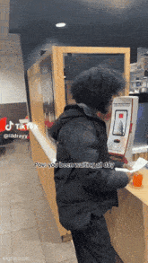 a man in a black jacket is standing in front of a mcdonald 's counter holding a receipt