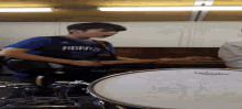 a boy wearing a hornets jersey playing a drum set