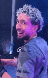 a man with white hair and a beard is smiling while wearing a purple shirt .