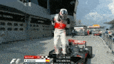 a man in a red and white mercedes racing suit stands next to a race car