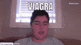 a man is sitting on a couch with his eyes closed and the word viagra is written on his face .
