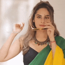 a woman wearing a black top and a green and yellow saree is holding a pair of glasses over her face