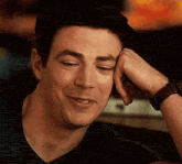 a man is smiling with his hand on his face .