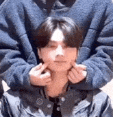 a close up of a person making a face with their hands on a man 's face .
