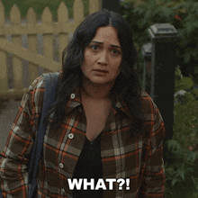 a woman in a plaid shirt says what in front of a fence