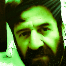 a close up of a man 's face with a beard and a green background