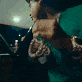 a man wearing a green shirt is holding a necklace