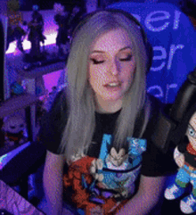 a woman wearing headphones and a dragon ball z shirt is sitting in front of a microphone