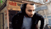 a man wearing headphones stands in front of a sign that says ' pondi par ' on it