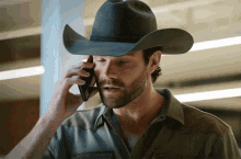 a man wearing a cowboy hat is talking on his cell phone