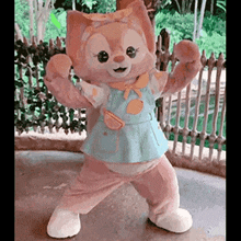 a stuffed animal is standing on its hind legs in front of a wooden fence .