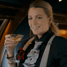a woman in a suit is holding a martini glass and smiling