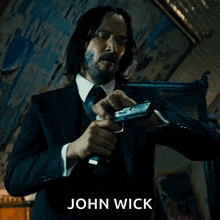 a man in a suit and tie is holding a gun and the name john wick is on the bottom of the image .