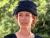 a woman wearing a black hat and a necklace is smiling