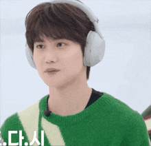a young man wearing headphones and a green and white sweater with the letters ch on it