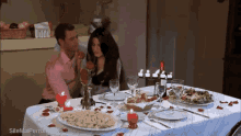 a man and a woman are sitting at a table with plates of food and candles ..