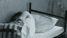 a woman is sleeping on a bed with a plaid blanket on it