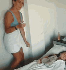a woman wrapped in a white towel is standing next to a child in a bed