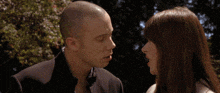 a man and a woman are standing next to each other and the woman is looking at the man .