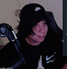 a man wearing a black nike hat is smiling in front of a microphone