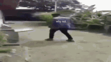 a man is walking down a street with a bag on his back and the words `` why not '' written on the ground .