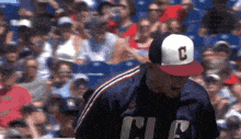 a baseball player wearing a cleveland hat stands in front of a crowd
