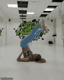 a woman is doing a handstand in front of a wall with graffiti that says ' graffiti '