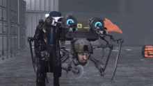 a man in a gas mask is standing next to a robot that has the letter a on it