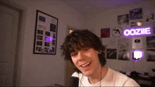 a young man is talking into a microphone in front of a oozie sign