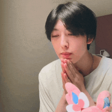 a young man with his eyes closed holds a pink stuffed animal