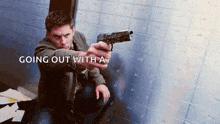 a man is sitting on the floor holding a gun in front of a brick wall .