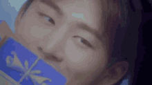 a close up of a person 's face with a blue gift box in his mouth .