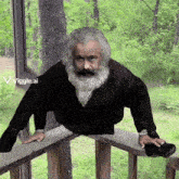 a man with a beard is standing on a wooden railing with the letters viggle.ai behind him