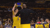 a basketball player for the lakers holds up his arms in the air